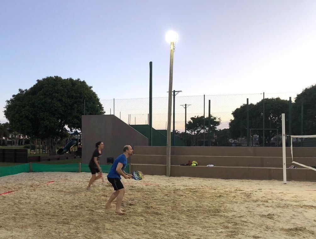 Pessoas jogando raquete em quadra de areia, foto